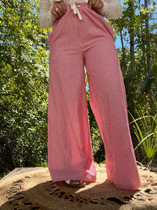 Red vertical stripe wide leg pants with elastic waist, shown on model outdoors.
