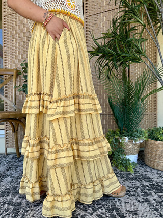 Pale yellow maxi skirt with gold embroidered vertical stripes and tiered ruffled hem details.
