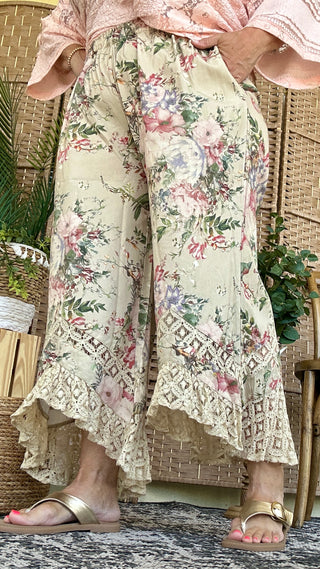 Cream wide-leg pants with pink and purple floral print and cream lace hem detail.
