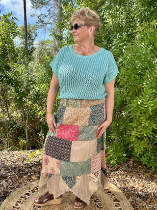 Light blue crochet short-sleeve top with patchwork maxi skirt in mixed prints and neutral tones.
