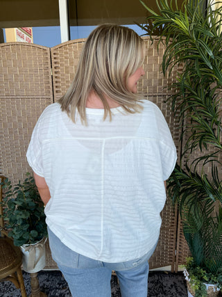 White textured dolman top with short sleeves and relaxed fit silhouette.
