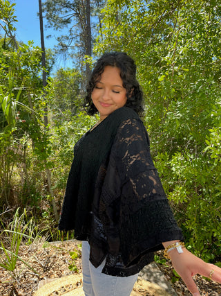 Black lace handkerchief hem top with sheer sleeves layered over white tank.
