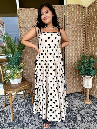 White maxi dress with black polka dots and black tie-shoulder straps.
