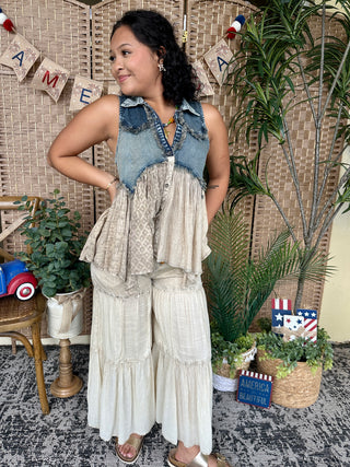 Denim and ivory tiered sleeveless top with collar and button front, paired with cream pants.
