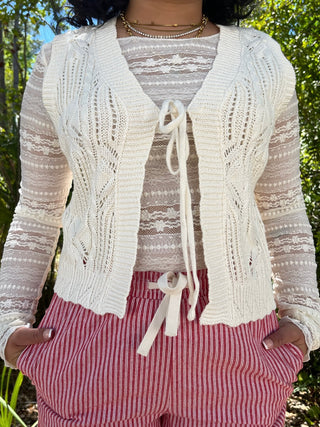 Ivory cable knit cardigan with lace sleeves and tie front closure over lace tank top.

