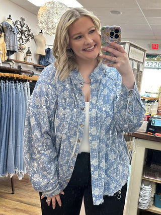 Blue paisley splatter button-up shirt with long sleeves worn over white top.
