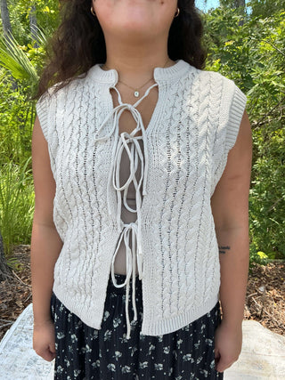 Bone cable knit sweater vest with a tie front detail, perfect for layering or a stylish standalone look