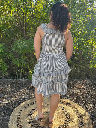 Black and white striped sleeveless dress with ruffled neckline and tiered ruffle hem.
