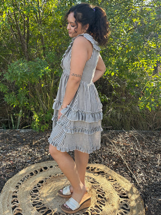Black and white striped sleeveless ruffle dress with tiered ruffled hem and open back detail.

