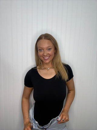Black short sleeve bodysuit with V-neckline and seamless construction on model.
