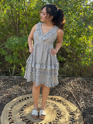 Black and white striped sleeveless dress with ruffled V-neckline and tiered hem.

