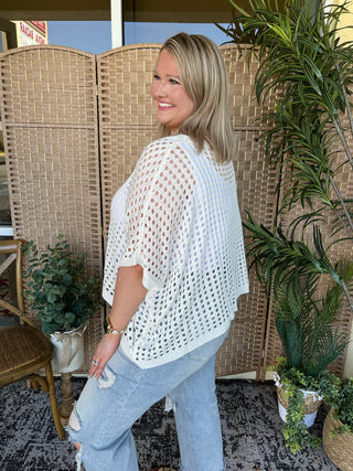White crochet dolman top with openwork pattern and short sleeves.
