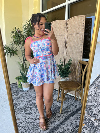 White sleeveless romper with blue and pink sardine can print and neon pink trim.
