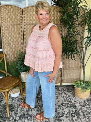 Pink sleeveless ruffle tank top with tiered ruffles, worn with blue jeans.
