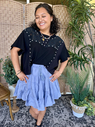 Black short-sleeve top with pearl beaded detailing paired with periwinkle midi skirt.
