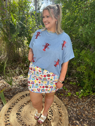 Light blue tee with red sequin lobster print scattered across front and sleeves.
