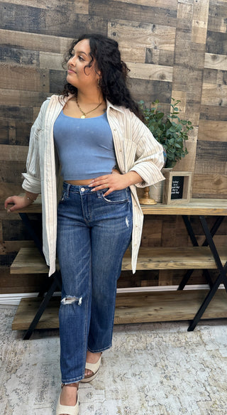 Ivory and black striped button-down shirt over blue ribbed crop top and distressed dark wash jeans.
