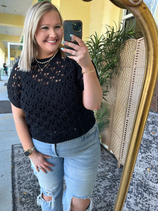 Black open weave short-sleeve sweater top with textured knit pattern.
