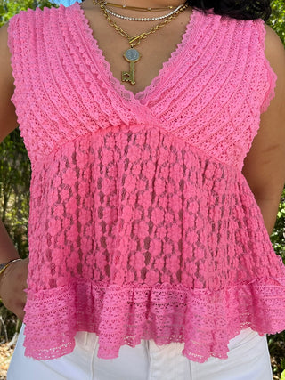 Pink lace sleeveless V-neck top with textured crochet pattern and ruffled hem.
