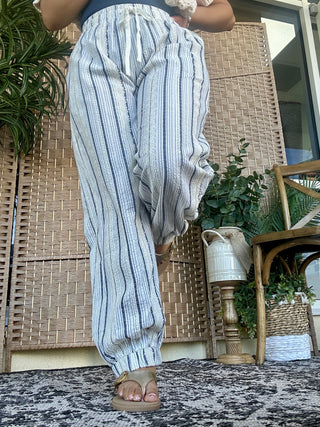 Light blue striped linen jogger pants with relaxed fit, styled casually on model.
