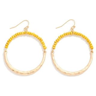 Yellow wood bead and gold hammered hoop drop earrings on a white background, showcasing artisanal elegance and modern design.