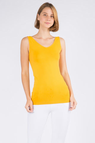 Mustard yellow sleeveless tank top with v-neckline on model wearing white pants.

