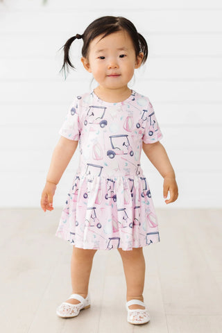Pink short-sleeve dress with purple golf cart pattern, fit and flare silhouette for toddler girls.
