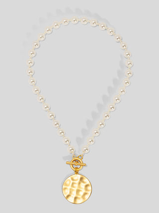 Cream pearl beaded necklace with gold toggle clasp and hammered gold disc pendant.
