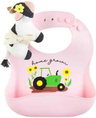 Mudpie Home Grown Cow Silicone Bib & Rattle set against a neutral background, featuring cute cow design and playful rattle.