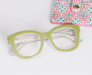 Green oversized reading glasses with colorful geometric patterned temples and matching printed case.
